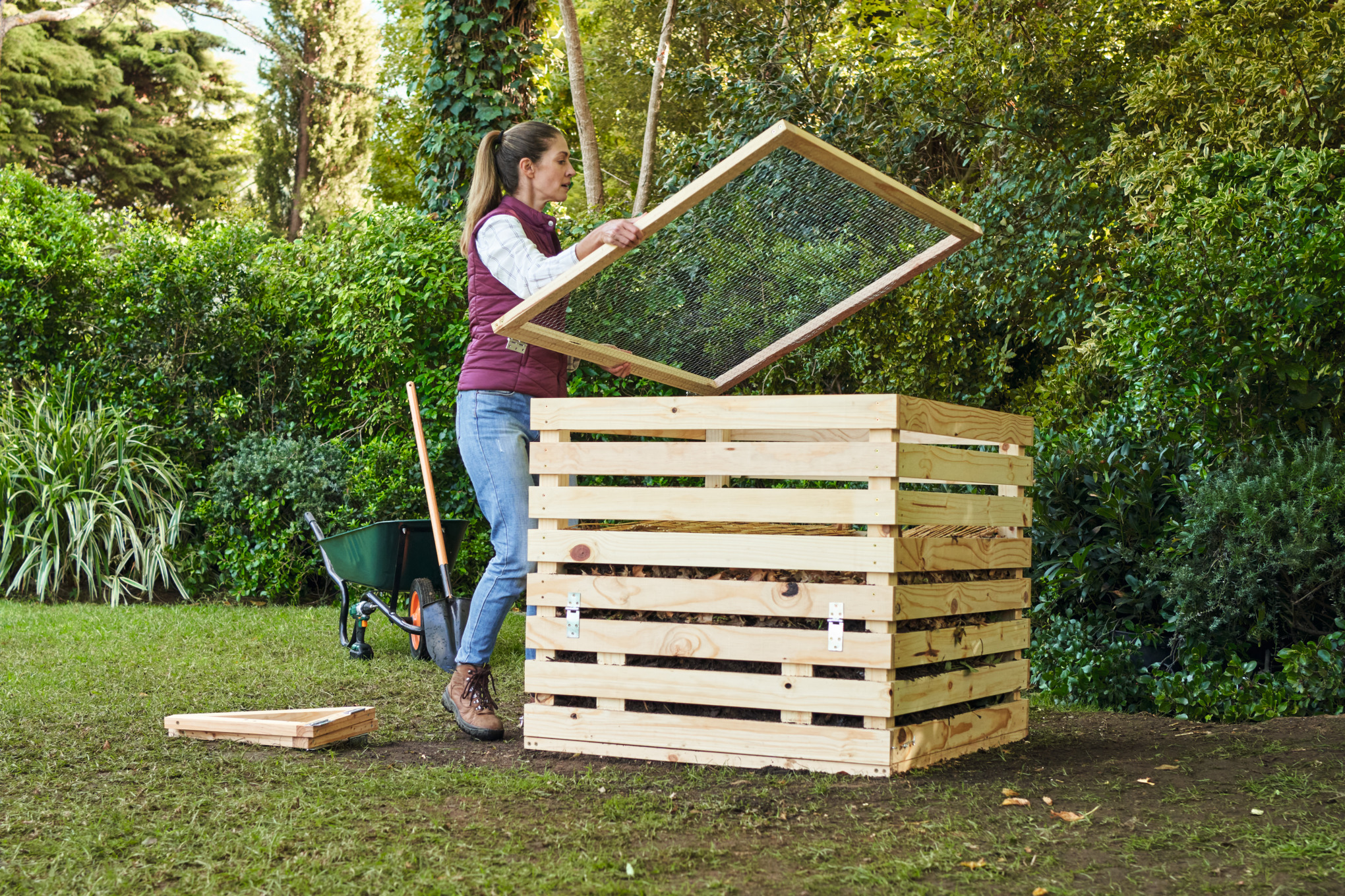 A woman on a garden property covering a homemade composter