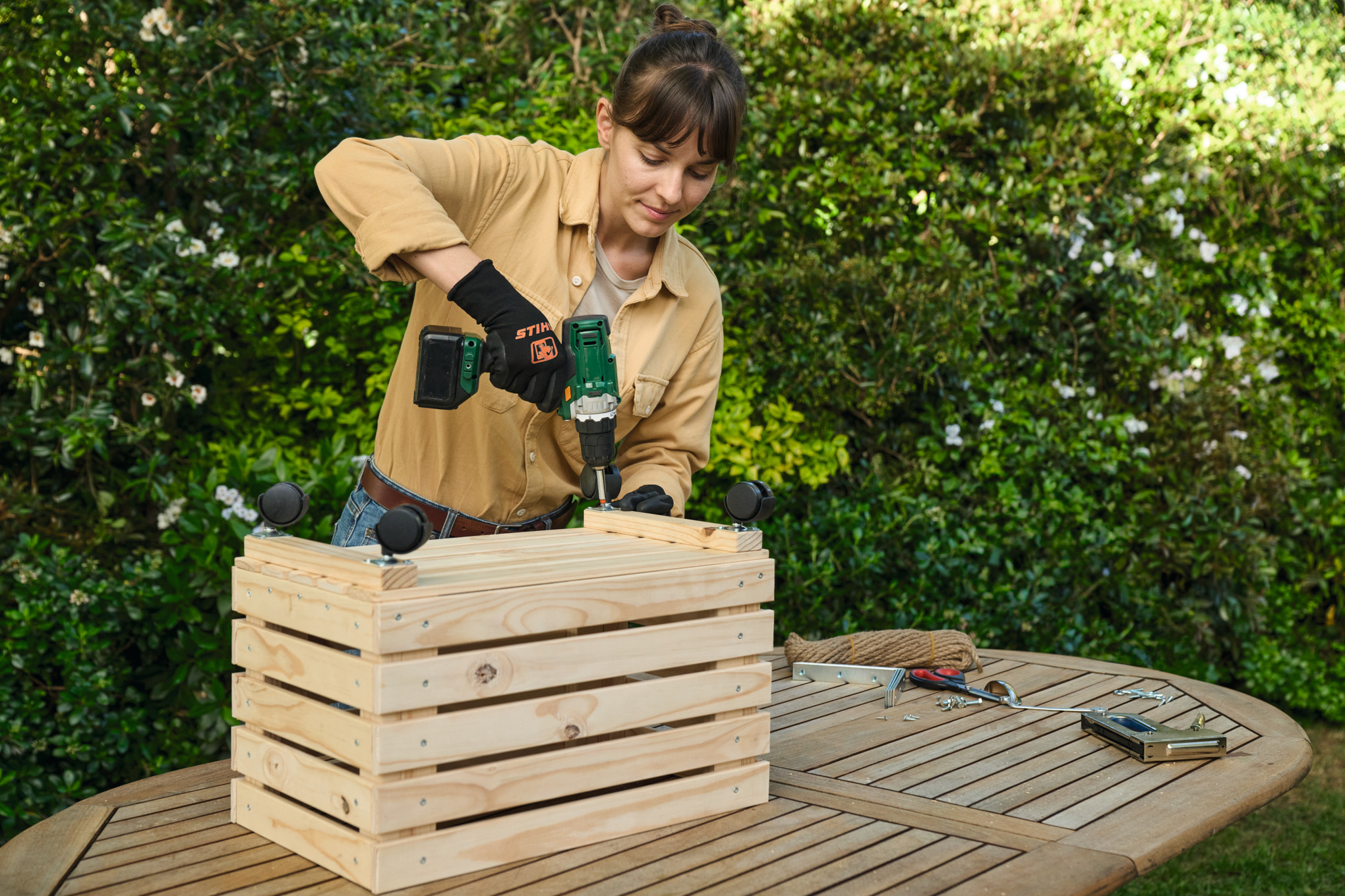 A woman screwing furniture castors to a planter
