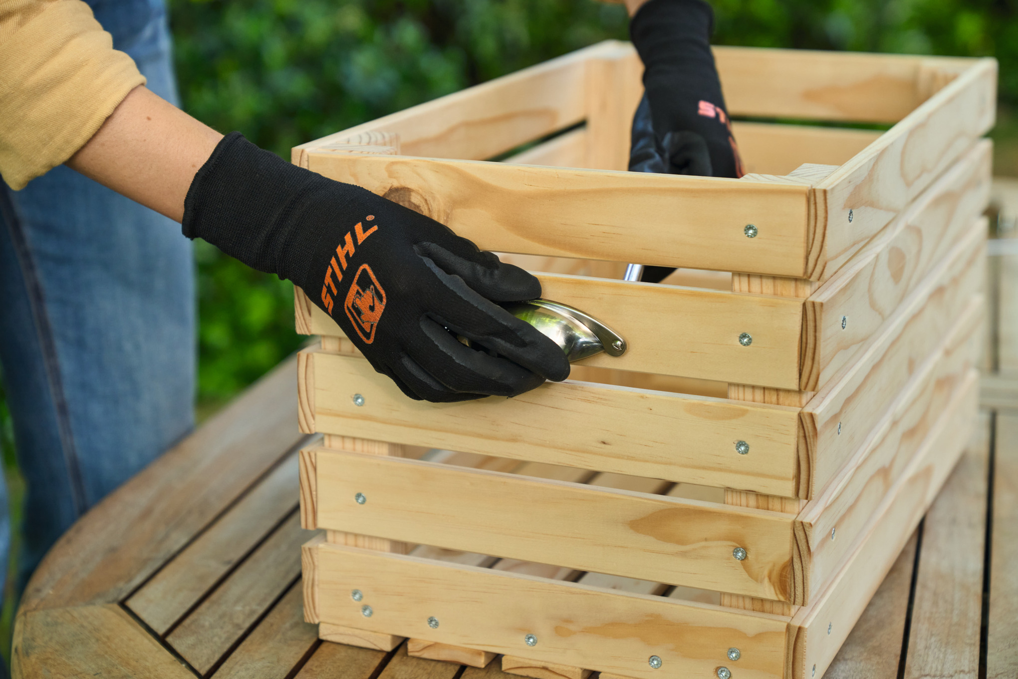 One person attaches side handles to the short sides of the planter