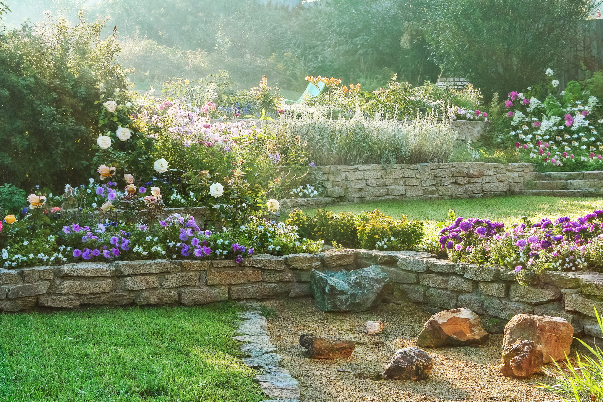 A sloping garden with stone walls, colourful flowers and lawns