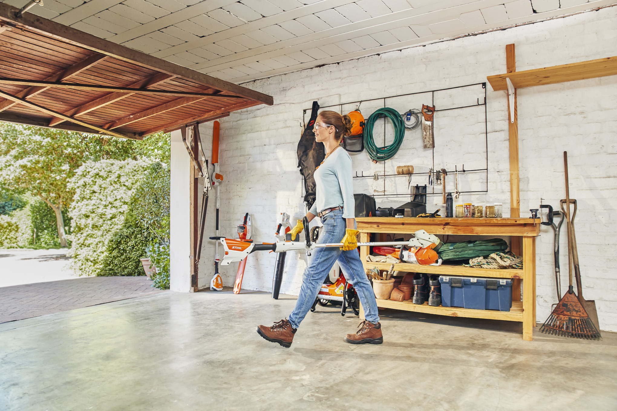 Woman Walking Out of Garage with STIHL Battery Trimmer