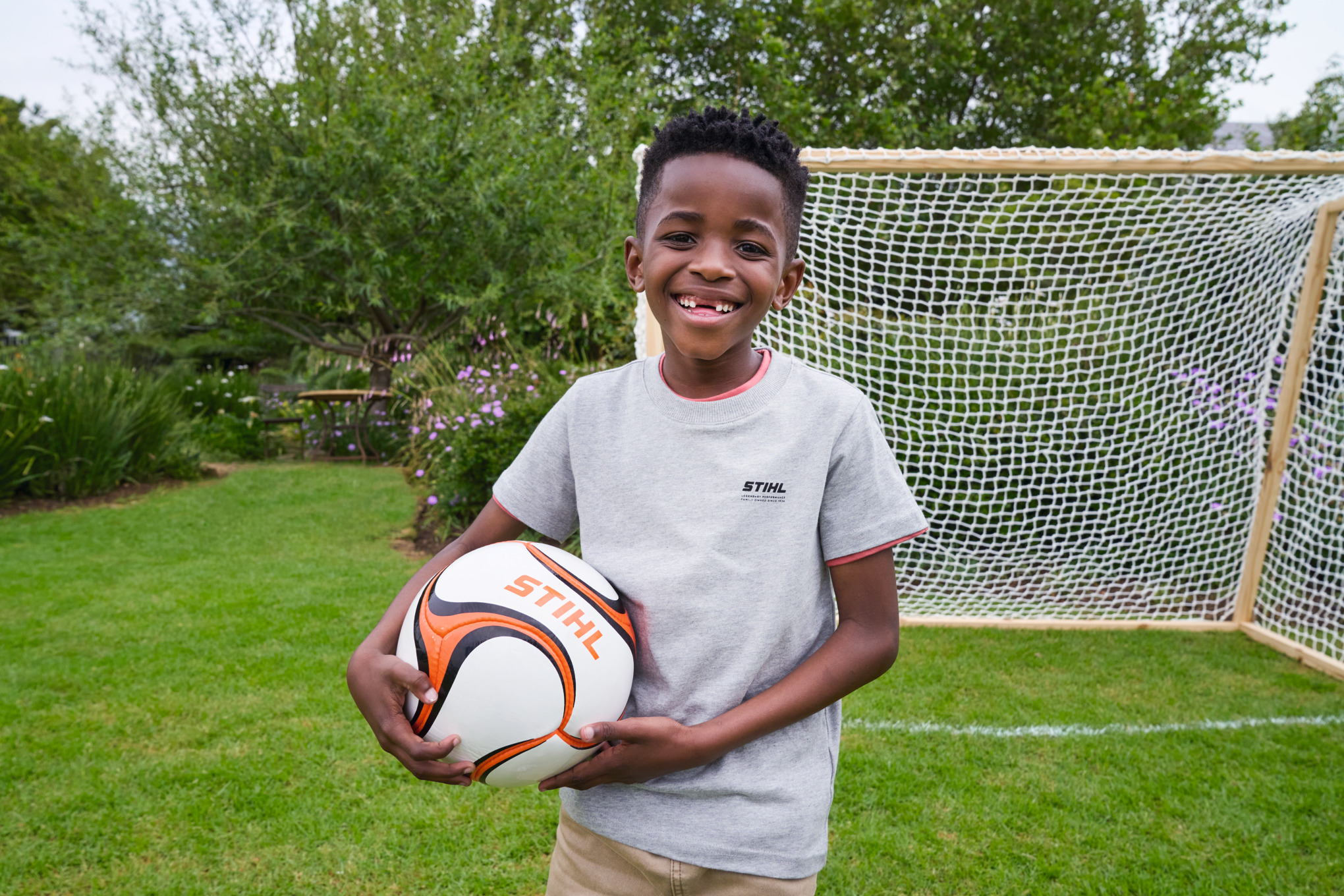 A beaming boy holding a STIHL football in his hand, in front of the new goal