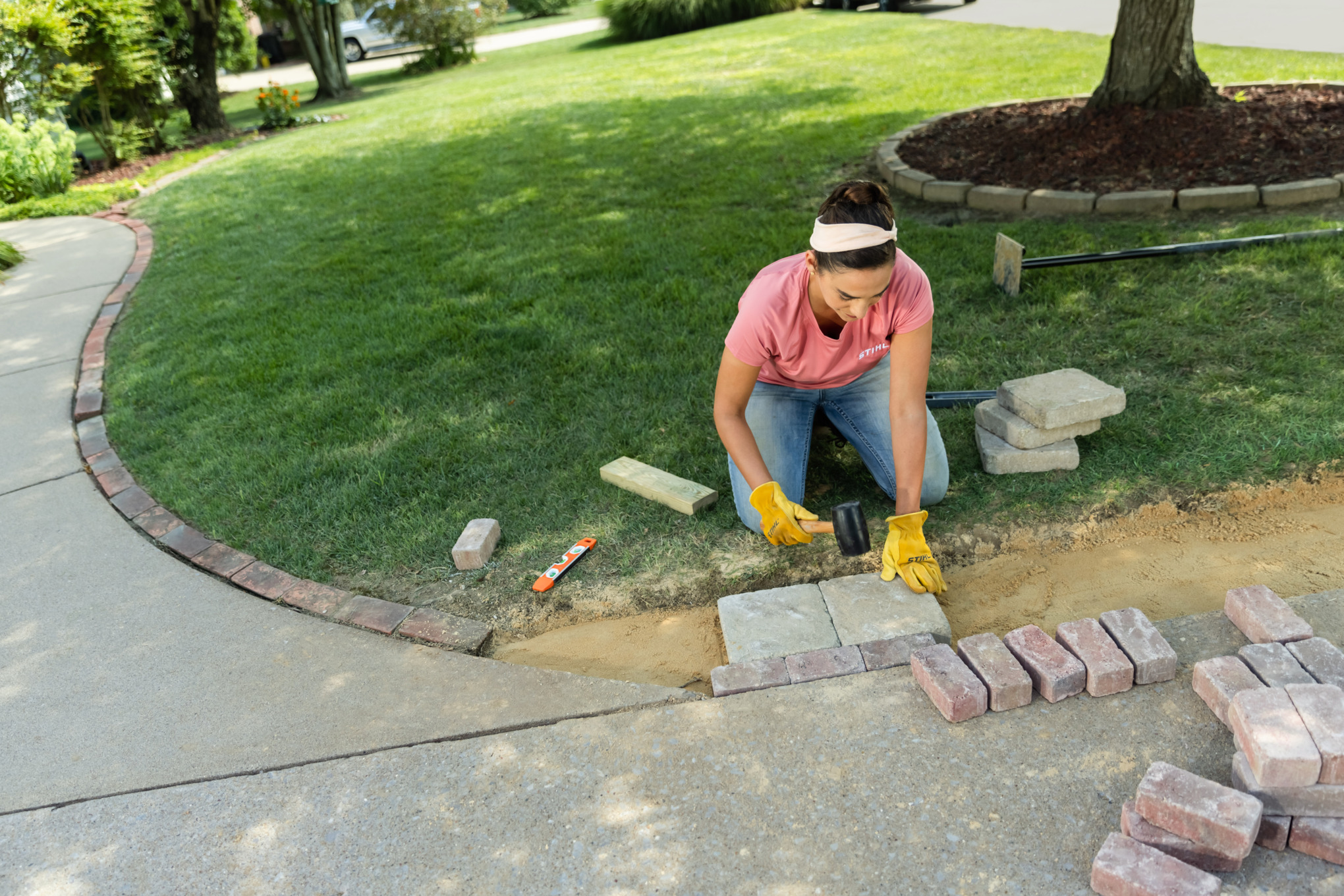 Sara Bendrick laying out pavers and tapping to level.