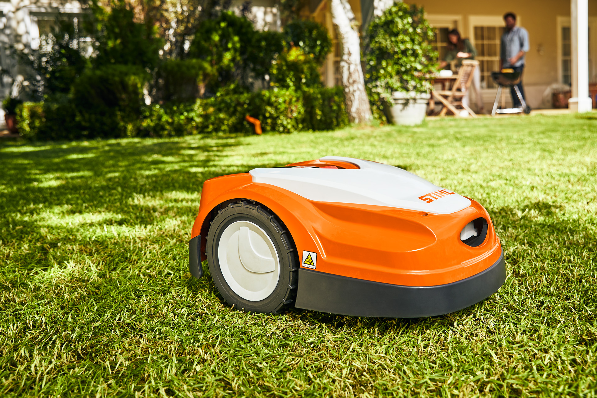 STIHL iMOW® RI 422 robotic mower on a green lawn in front of a house