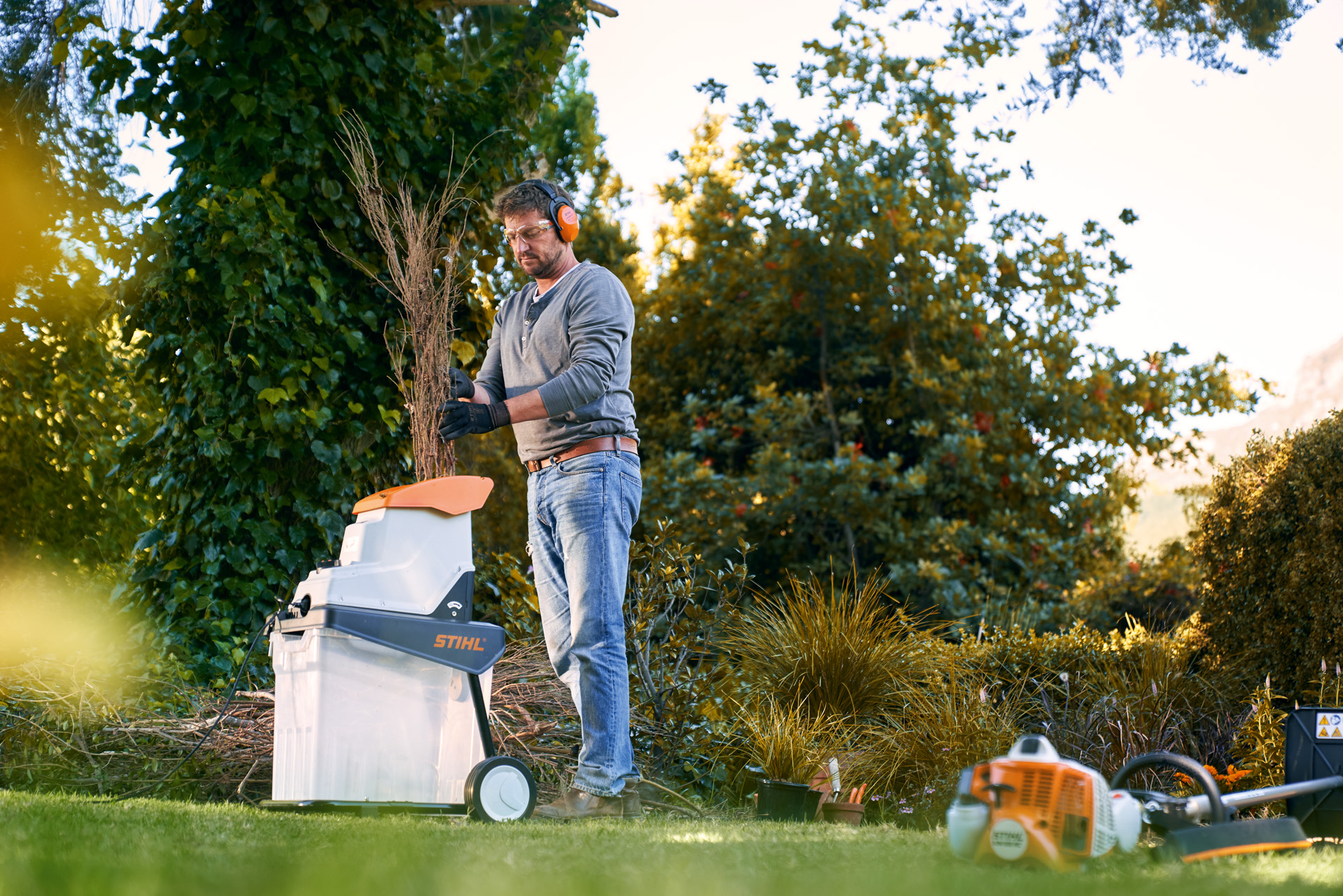 A man feeding tree cuttings into a STIHL GHE 140 L electric vacuum shredder