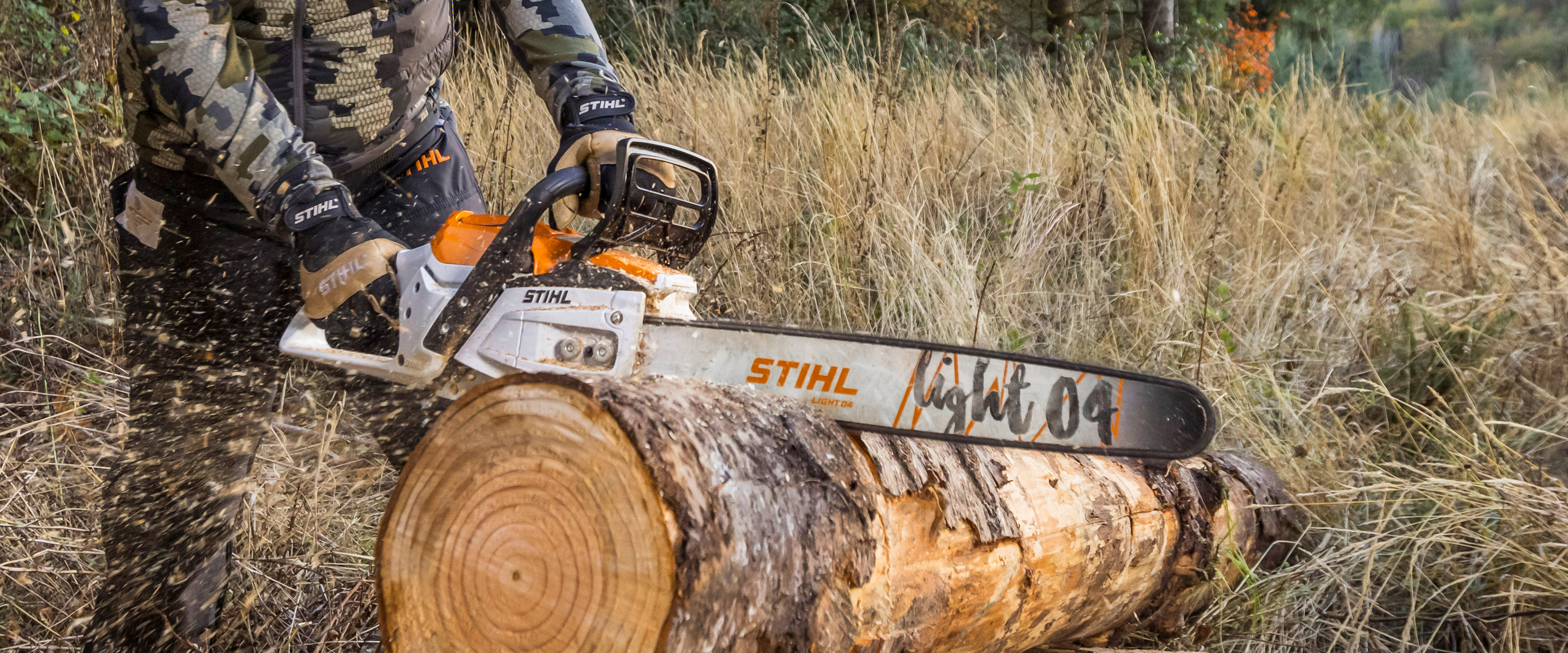 Stihl chainsaw being used to cut log in a field