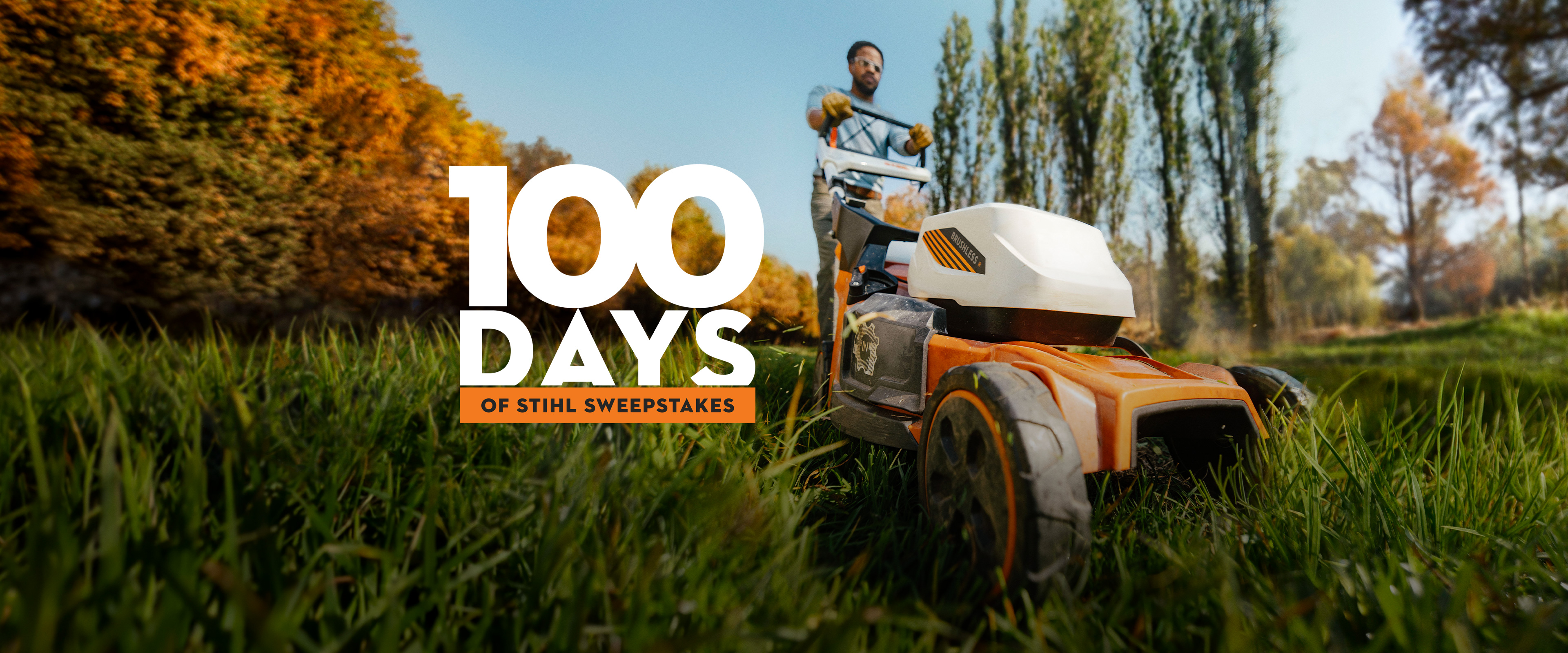 Person pushing a battery-powered lawn mower through tall grass in an outdoor setting, with promotional text reading “100 Days of STIHL Sweepstakes."