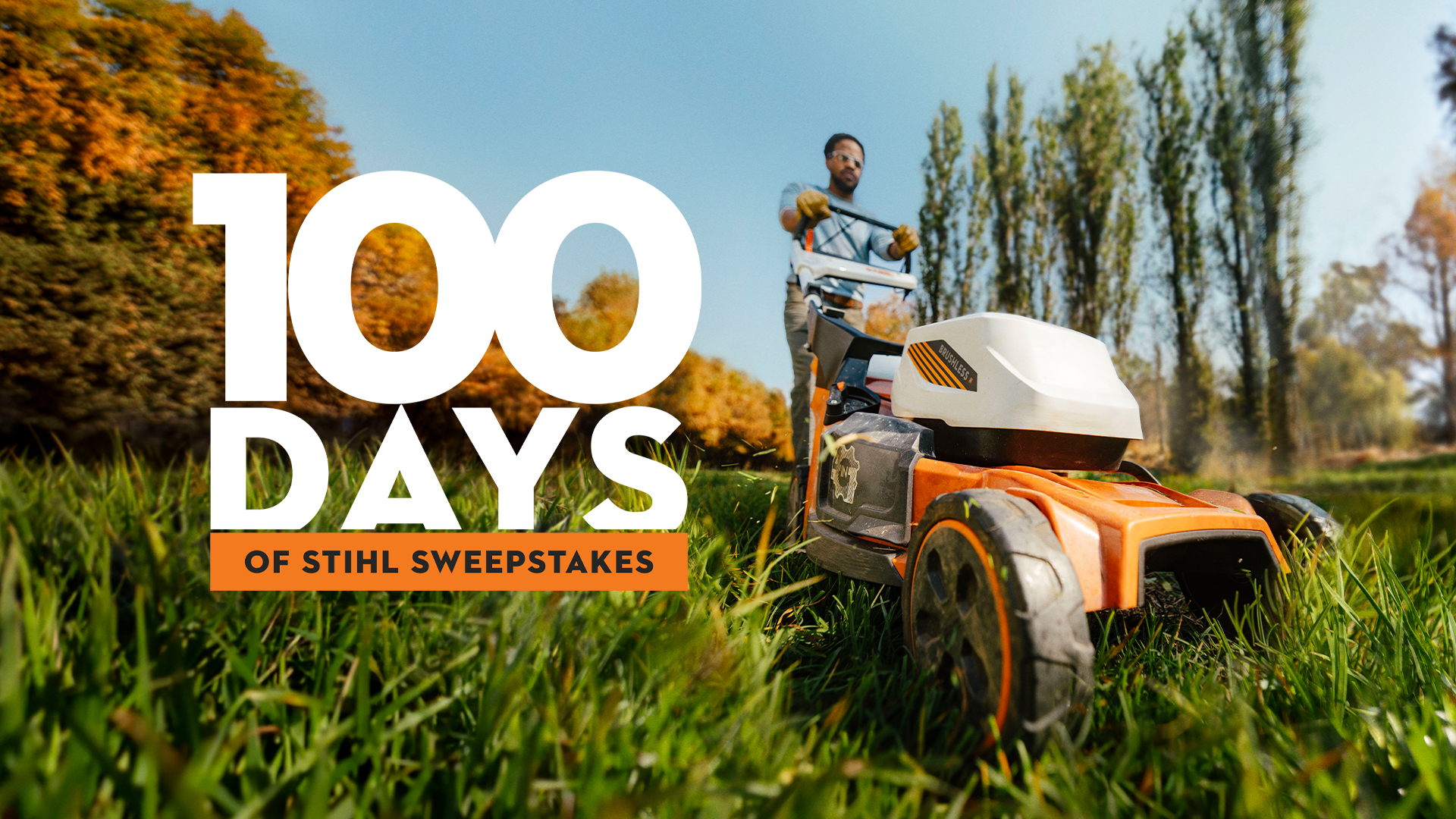 Person pushing a battery-powered lawn mower through tall grass in an outdoor setting, with promotional text reading “100 Days of STIHL Sweepstakes.