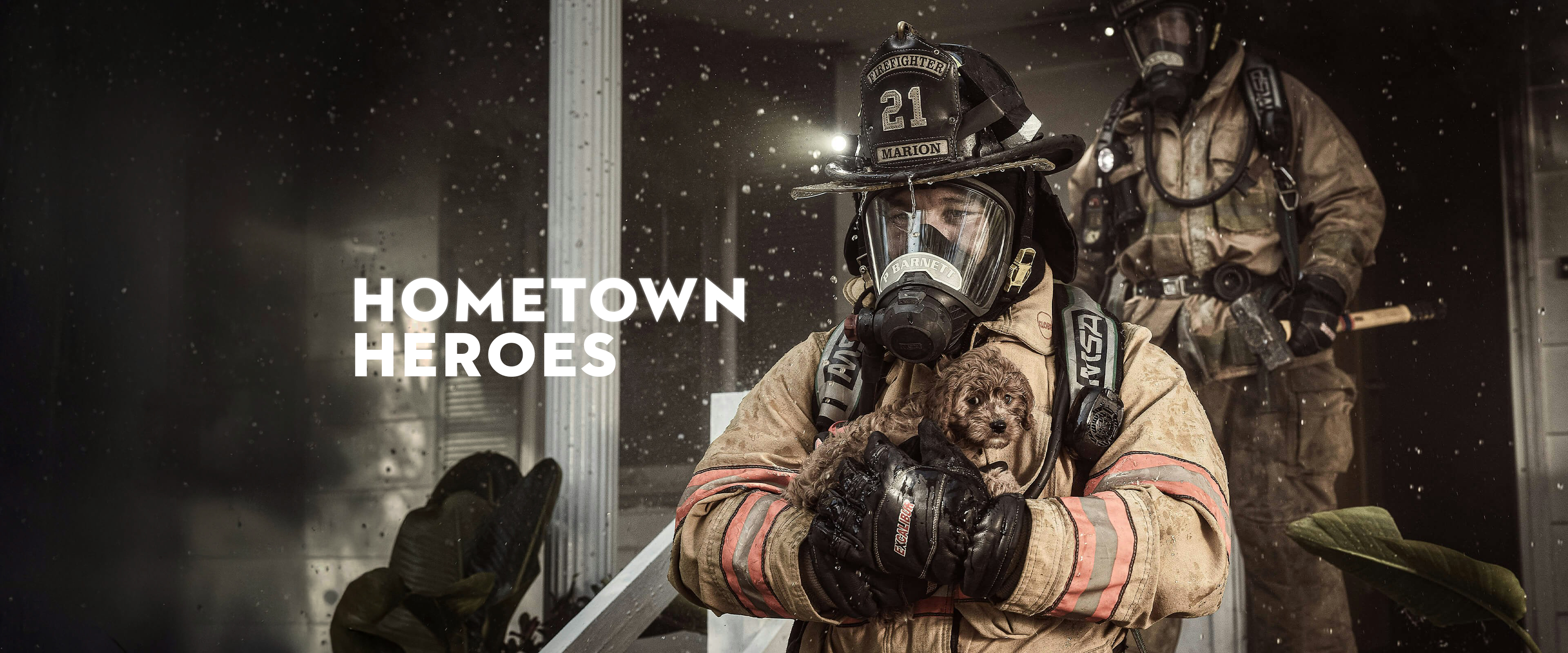 Firefighter walking out of burning house with puppy in hands