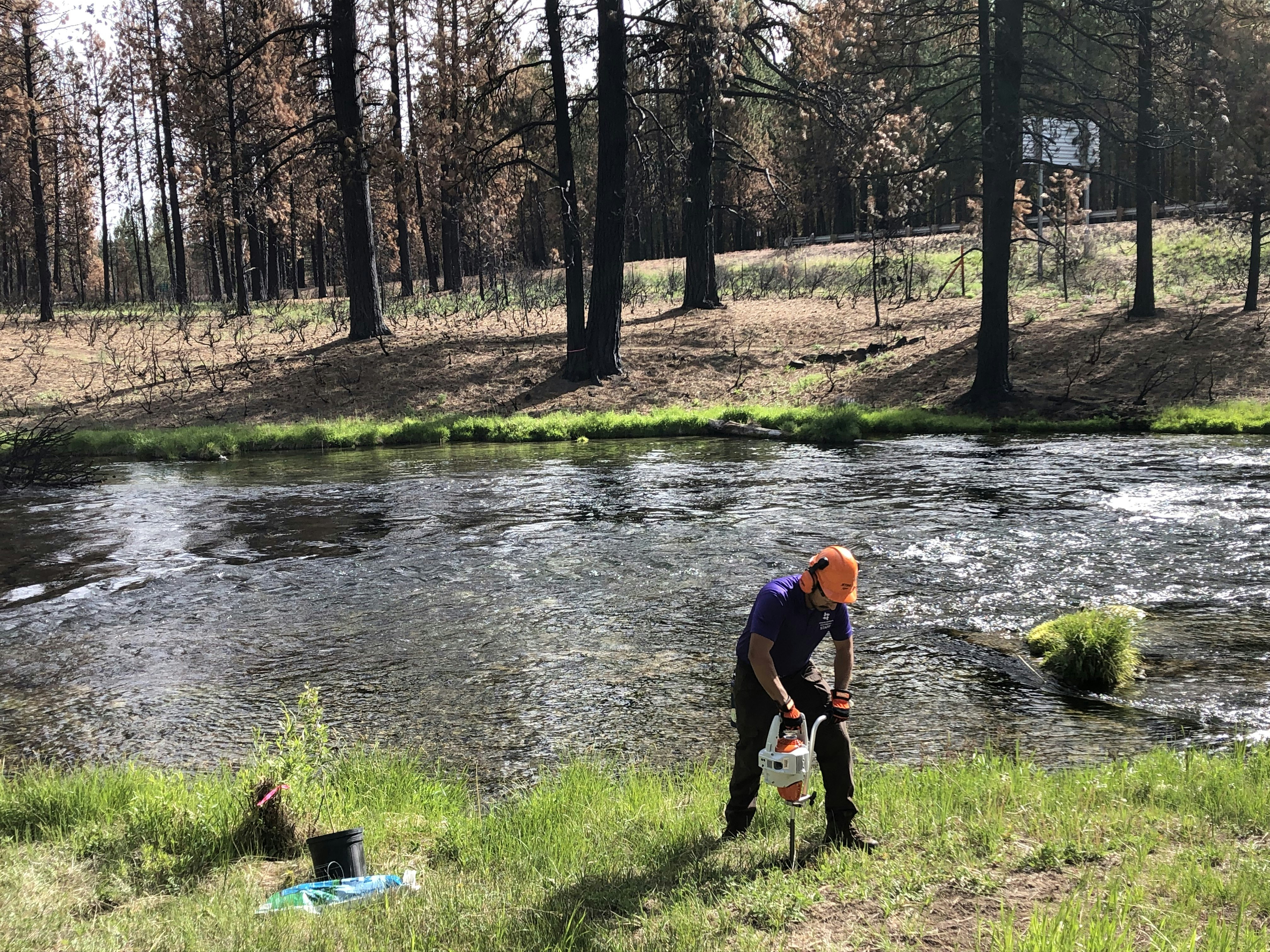 Man using auger by river