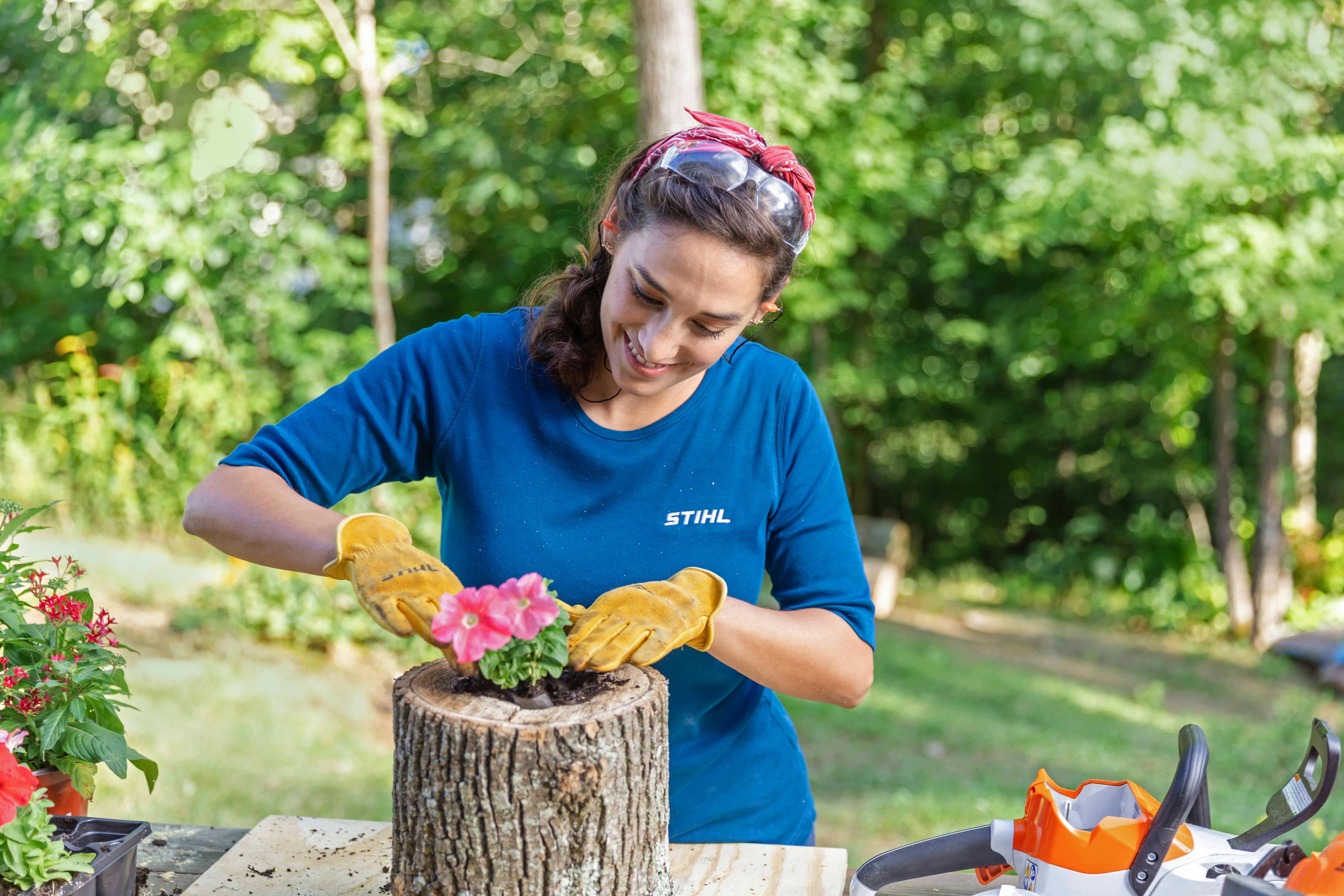 Sara Bendrick planting flower in log planting