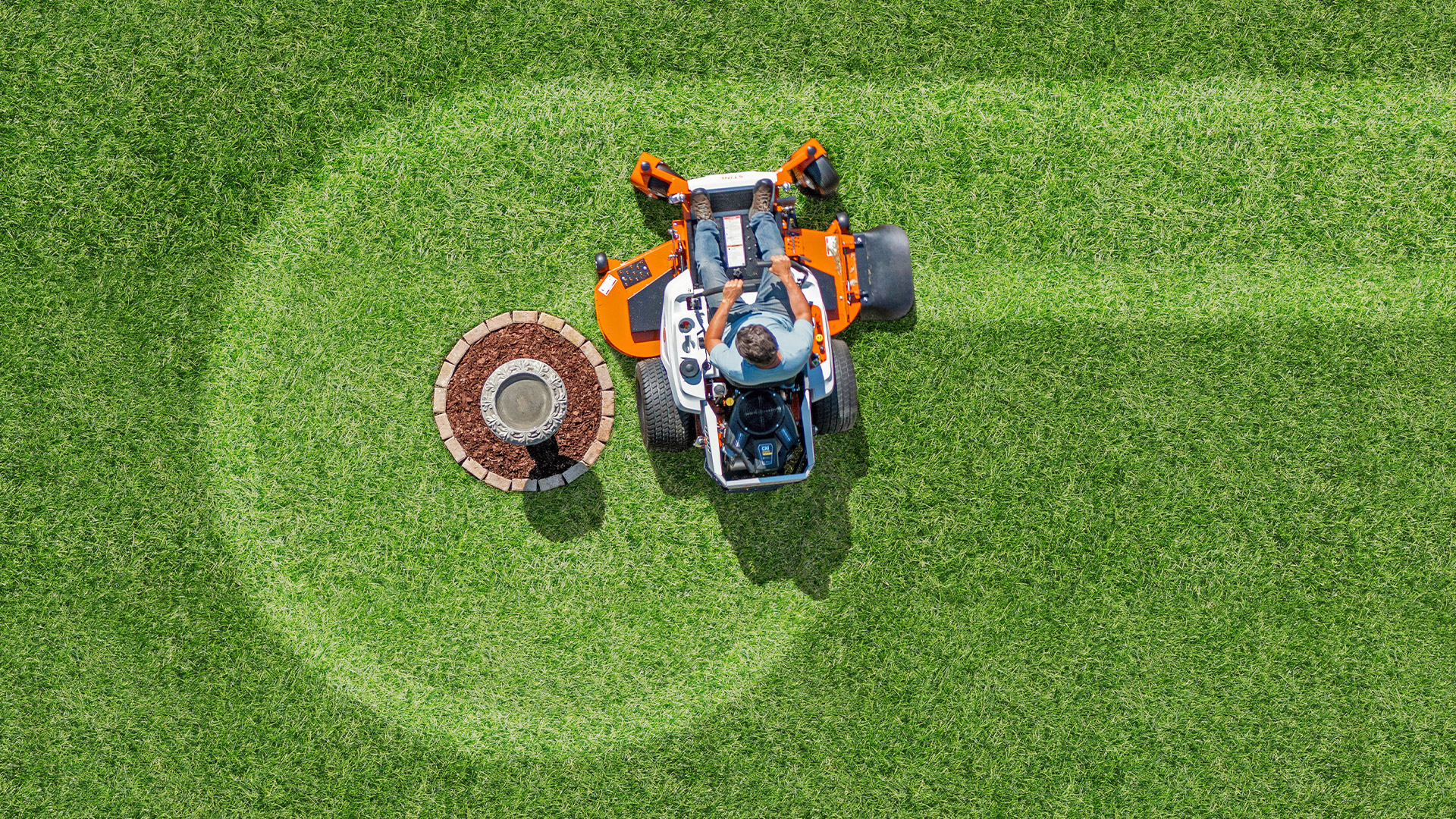 Aerial view of a STIHL zero-turn mower cutting a curved pattern in a green lawn.