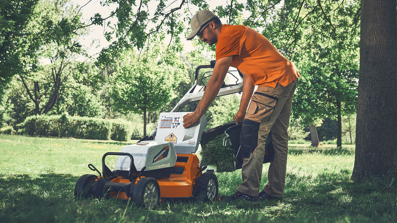 Homeowner emptying the grass bag on a STIHL gas mower with a Mono-Comfort handlebar.