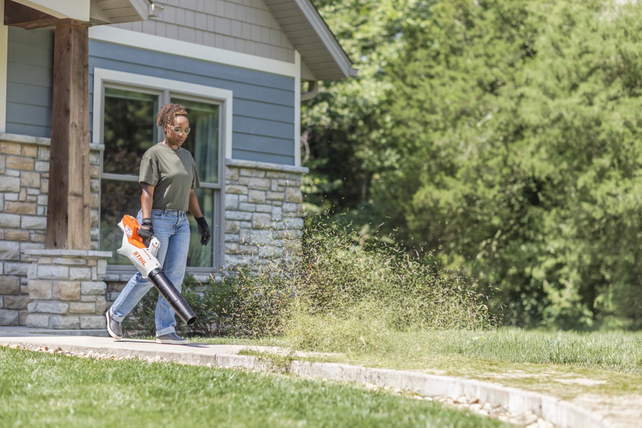 Woman using STIHL BGA 60 to blow grass off patio