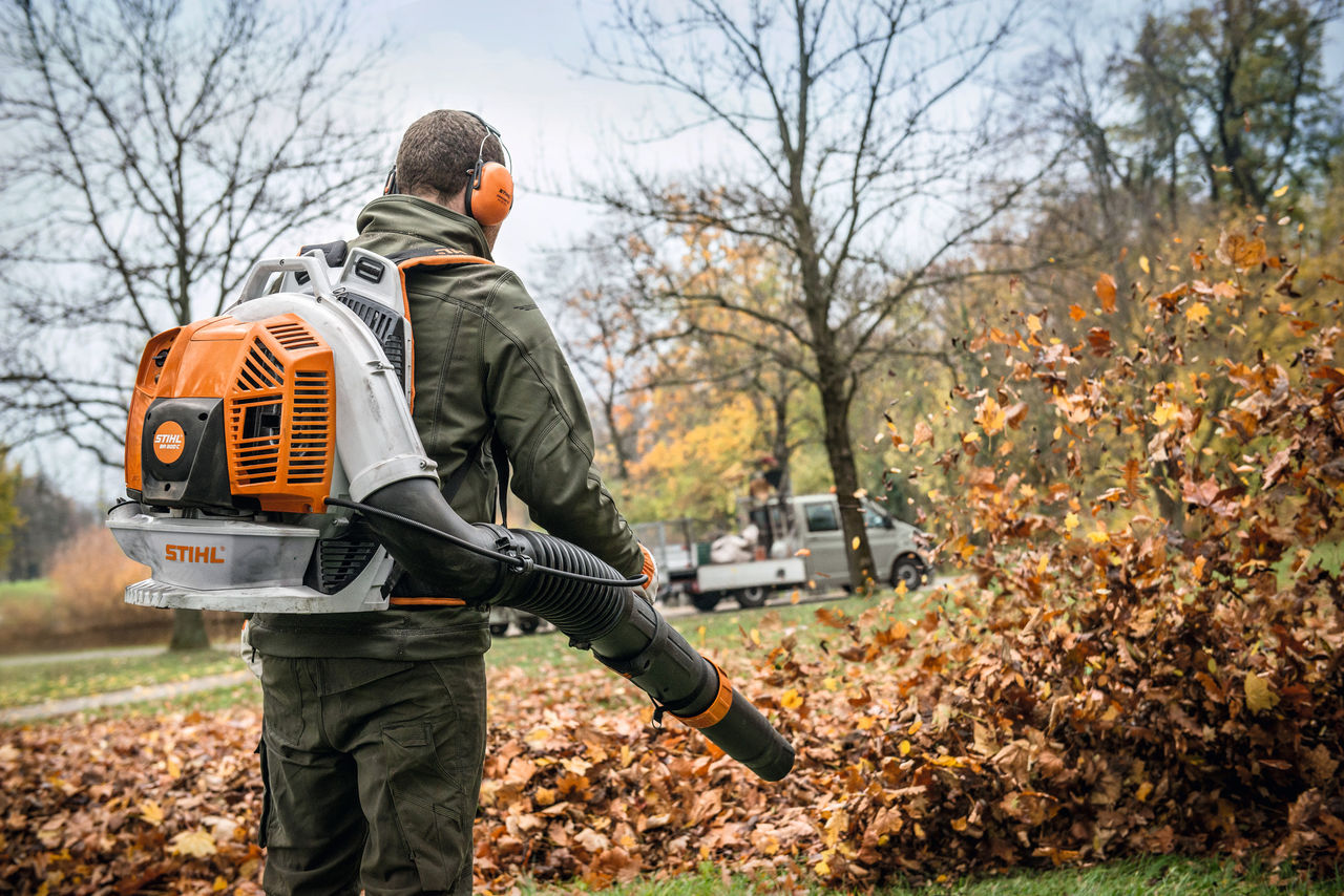 Man using STIHL BR 200 backpack blower to blow leaves off lawn