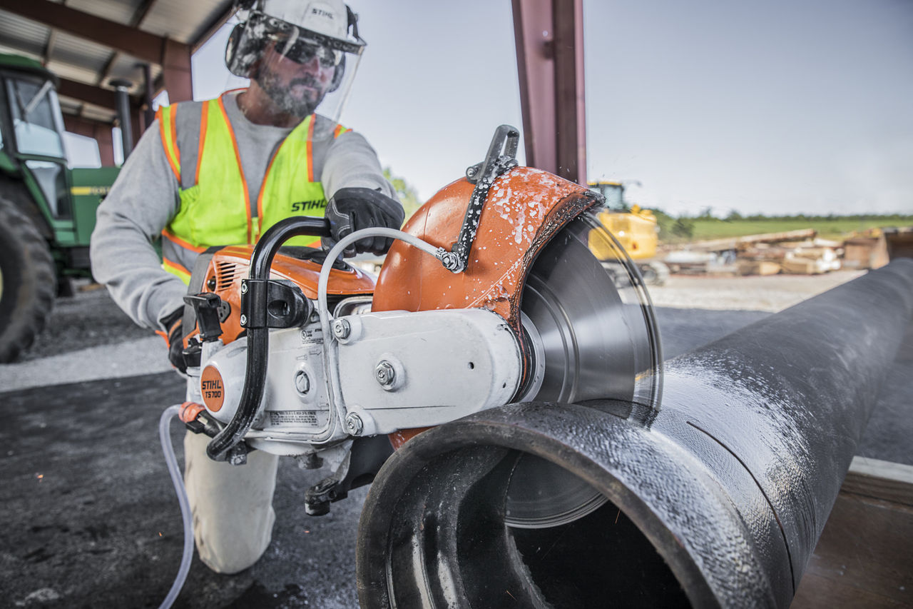 Construction Worker Using STIHL TS 700 on Large Metal Pipe