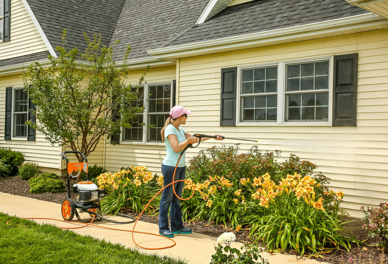 Woman pressure washing side of house with STIHL Pressure Washer