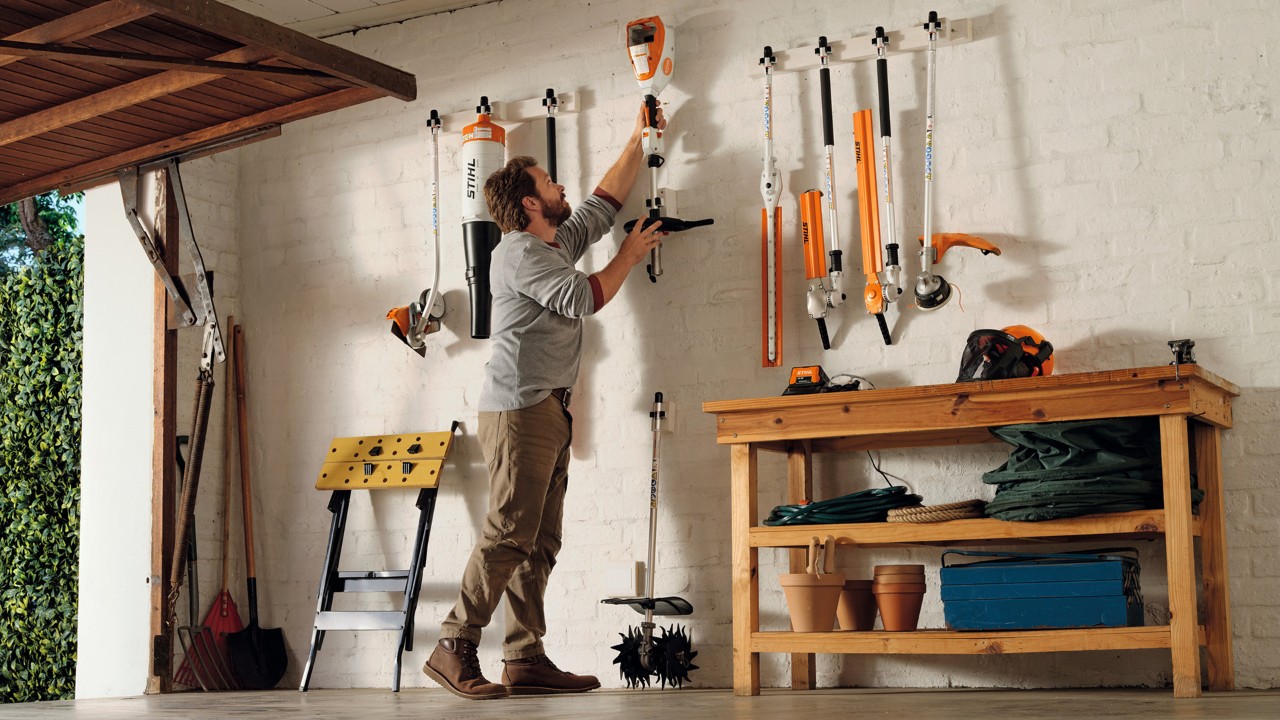 STIHL battery-powered outdoor tools organized on a wall in a garage