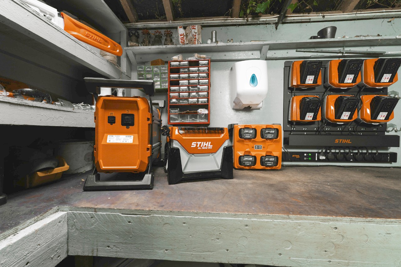 Centralized STIHL battery charging and storage system installed in a workshop environment.